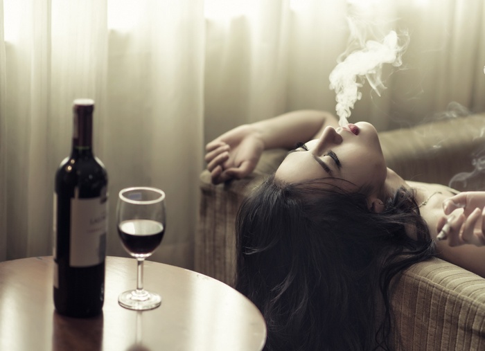 Woman smoking with wine bottle and glass