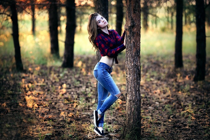 Woman in torn jeans and plaid shirt in forest