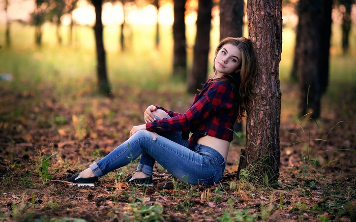 Young woman in torn jeans and plaid shirt in forest