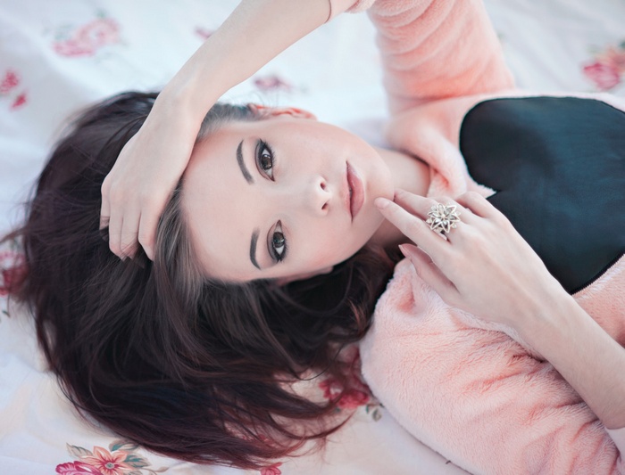 Woman with hands in hair wearing a pink top and ring