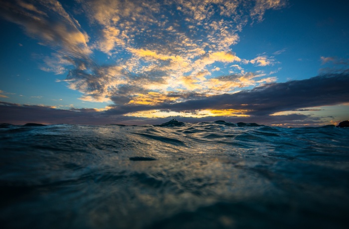 Ocean waves under a dramatic sunset sky with clouds