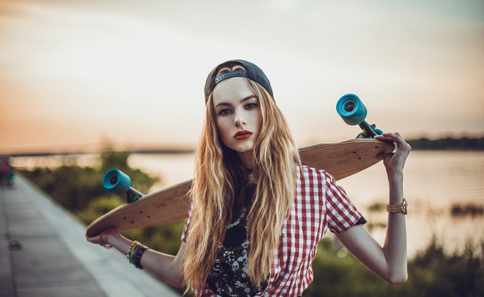 Woman with longboard wearing a baseball cap