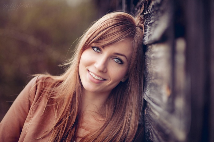 Woman with blonde hair leaning against wood