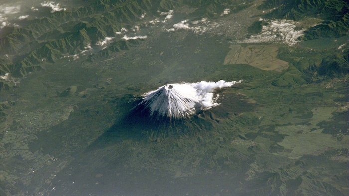Aerial view of Mount Fuji volcano with snow-capped peak and shadow