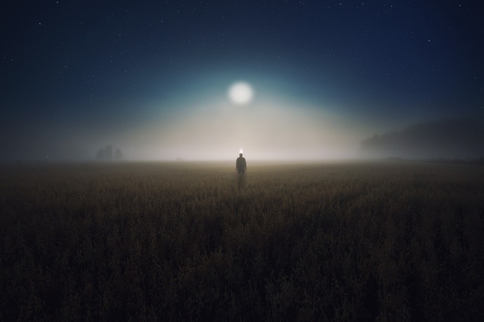 Man standing in a misty field at night