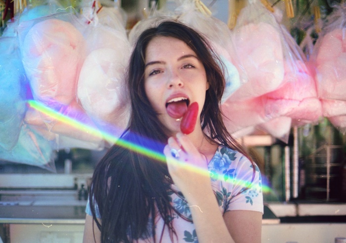 Woman eating a red popsicle with cotton candy