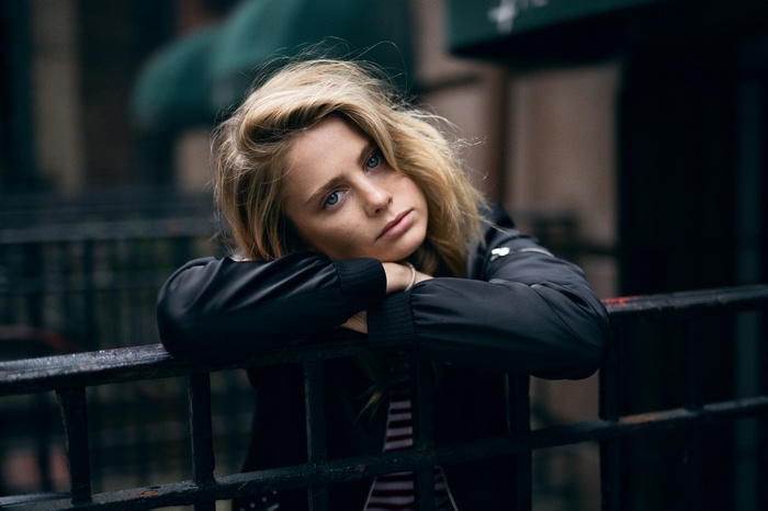 Blonde woman leaning on a fence outdoors