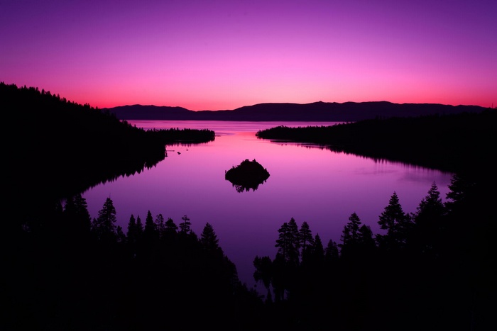Purple sunset over a lake with an island and forest