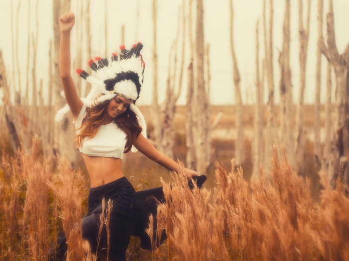 Woman in Native American Headdress Dancing in Field