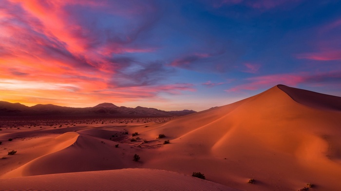 Desert sand dunes at sunset with colorful sky