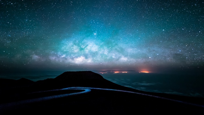Night sky over a mountain landscape with city lights