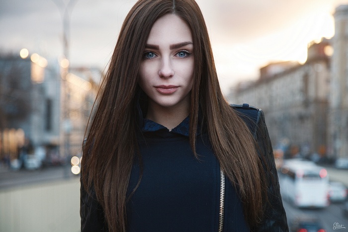 Woman with long brown hair and blue eyes in a city