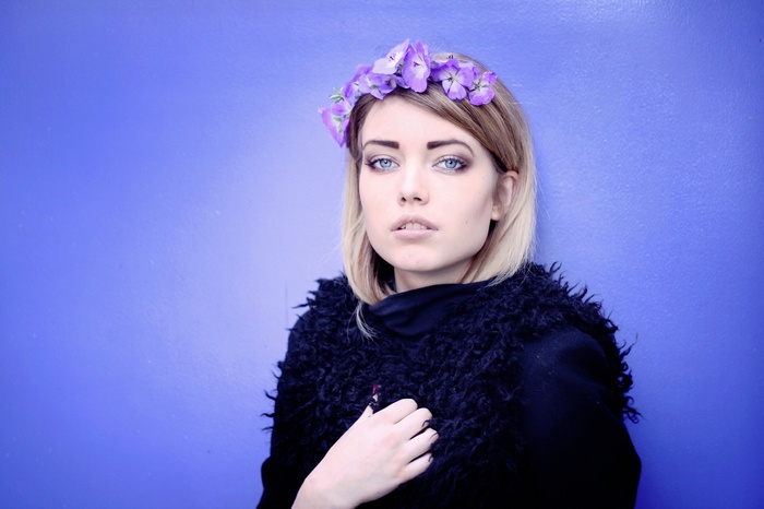 Woman with flower crown and black coat