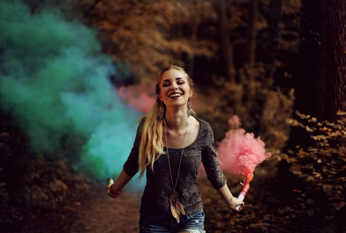 Woman holding smoke bombs in a forest