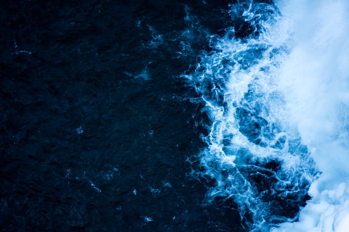 Dark blue water with white foam waves