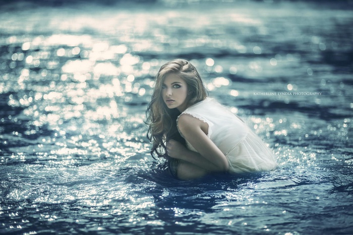 Woman in white dress sitting in sparkling water