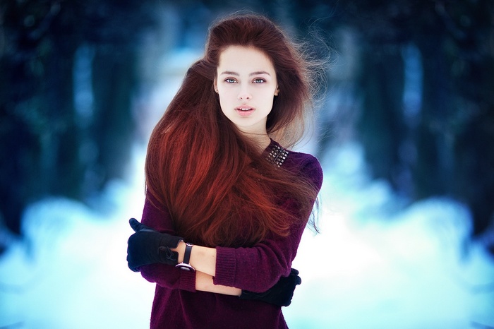 Woman with long red hair wearing a purple sweater and gloves