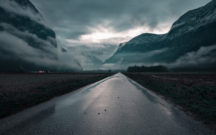 Wet road through mountains and fog