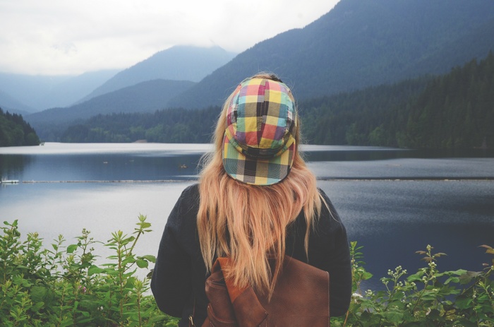 Woman with colorful hat looking at a lake and mountains
