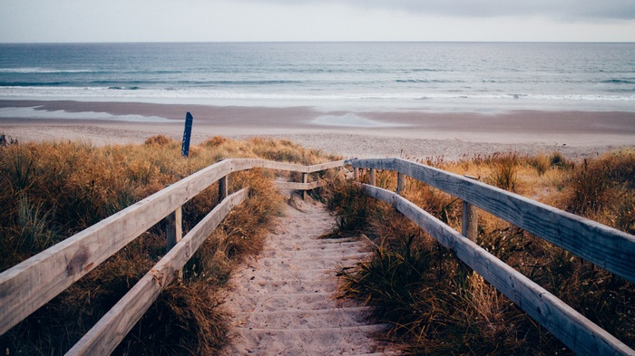 Wooden stairs leading to a sandy beach and the sea