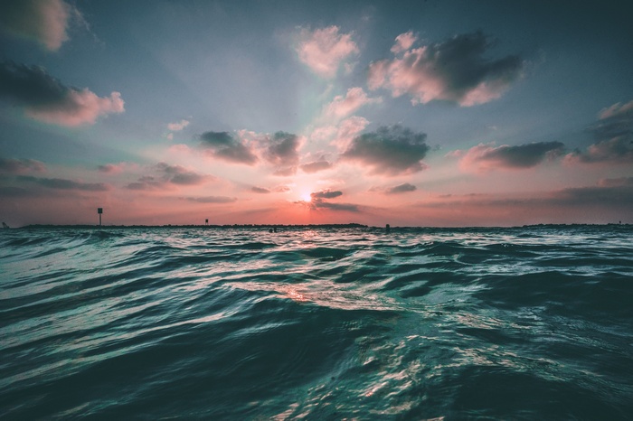 Sunset over the ocean with waves and clouds