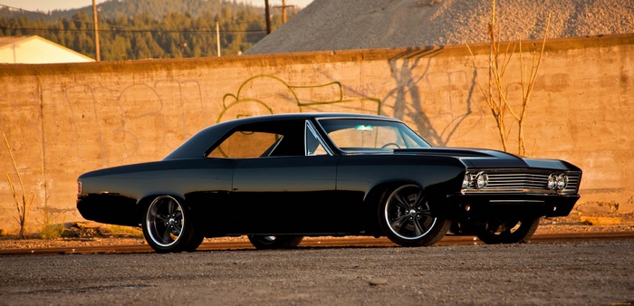 Black Chevrolet Impala parked by a concrete wall