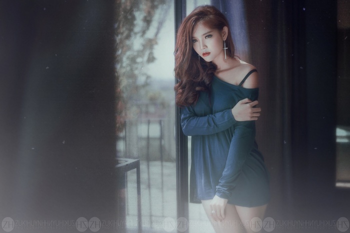 Asian woman in a blue dress by the window