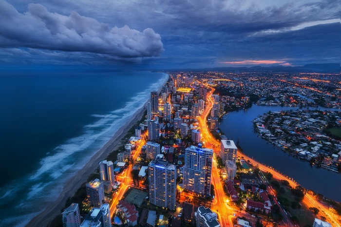 Cityscape at dusk with ocean and storm clouds