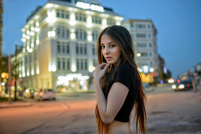 Woman with long hair in front of a hotel at night