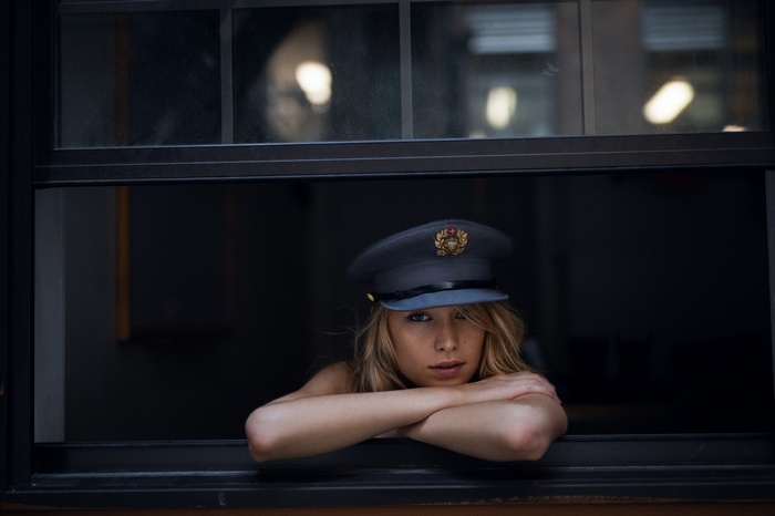 Woman in a military-style hat looking out a window
