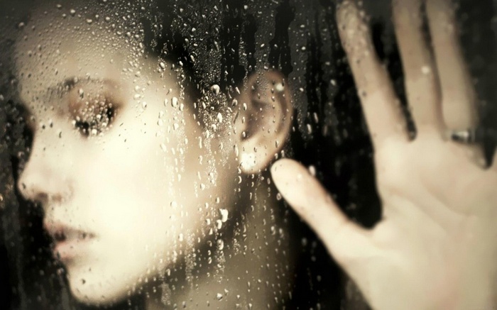 Woman's face behind a rain-covered window