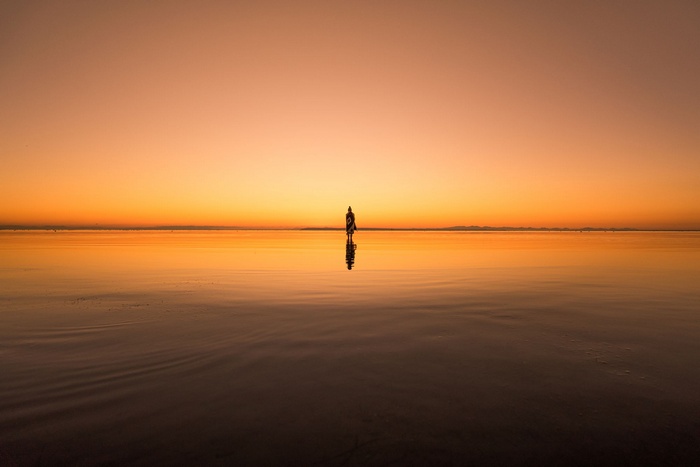 Woman standing in the ocean at sunset