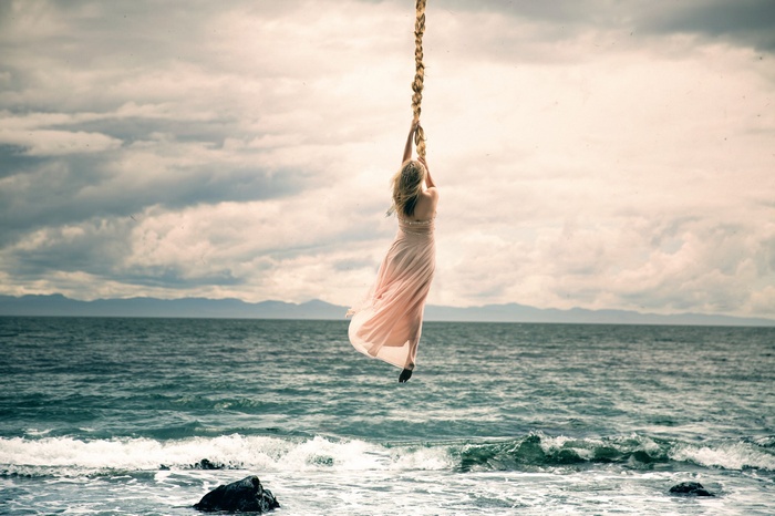 Fantasy girl swinging over the sea