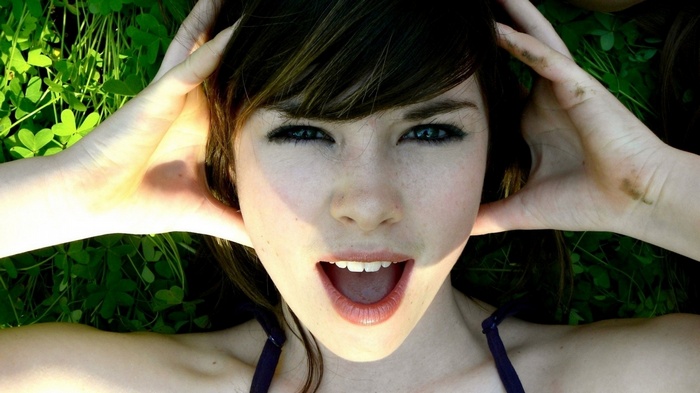 Woman lying on grass with hands on head