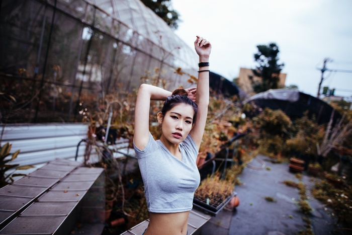 Asian woman with arms up in an outdoor greenhouse
