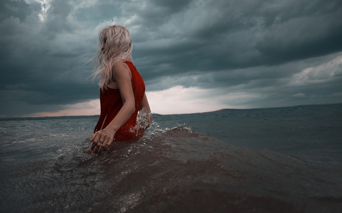 Woman in red dress in stormy ocean waves