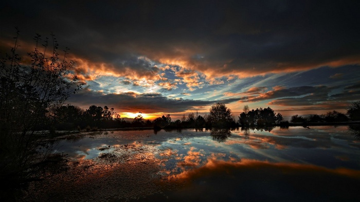 Sunset over a lake with dramatic clouds and reflections