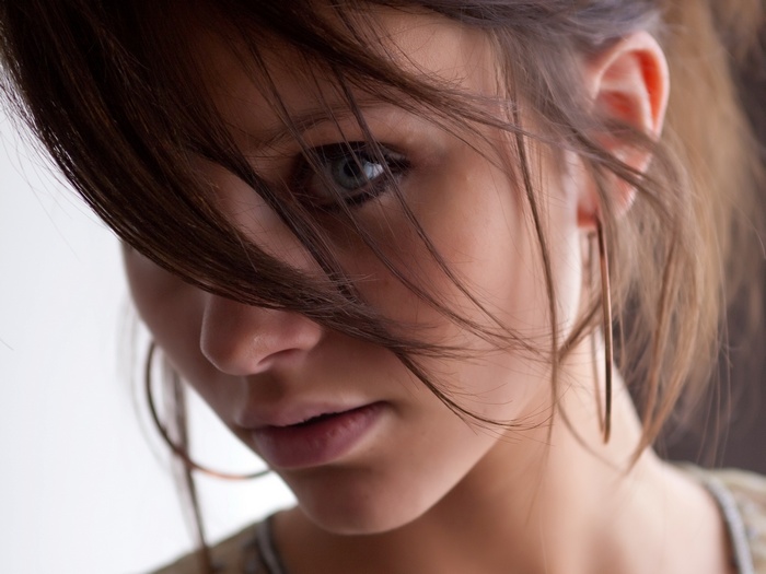 Close-up of a woman's face with hair obscuring her eye