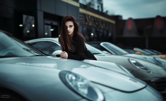 Brunette model leaning on a Porsche car