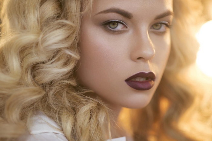 Portrait of a woman with blonde curly hair and dark lipstick