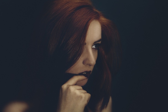 Woman with red hair and finger on lips