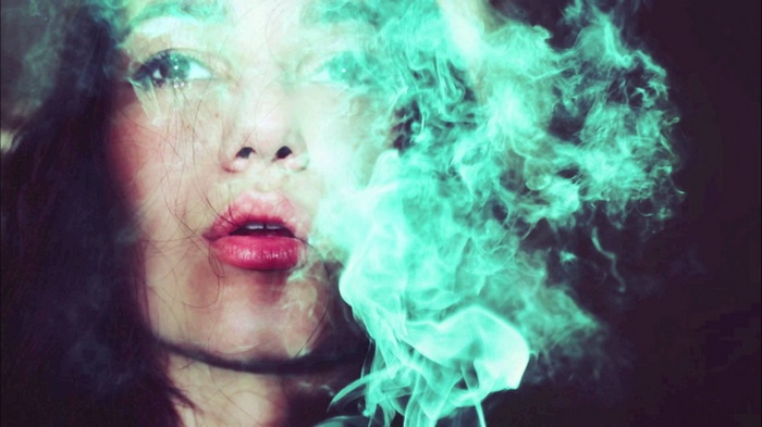 Woman exhaling colored smoke