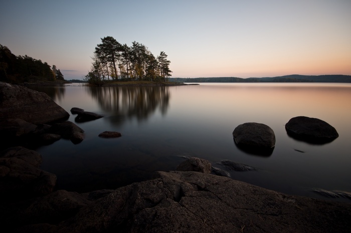 Calm lake with island and rocks at sunset