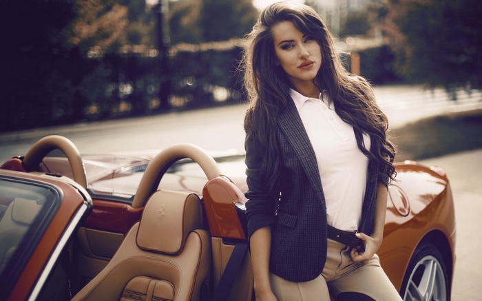 Woman in blazer leaning on a red Ferrari convertible