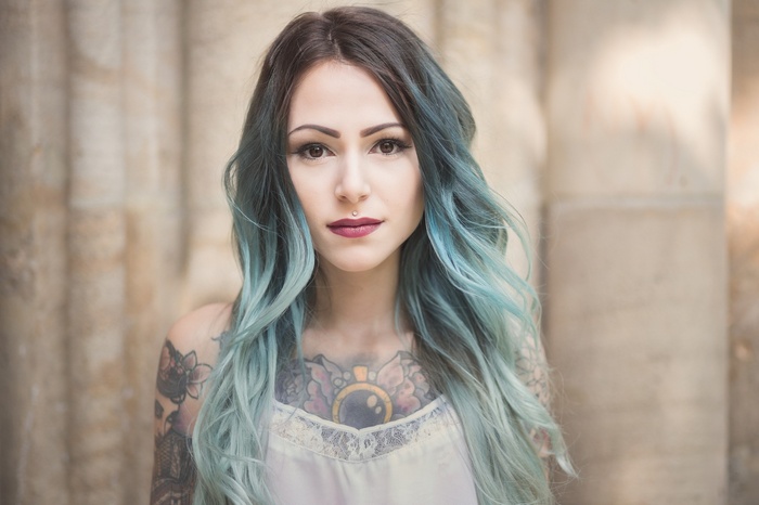 Woman with blue dyed hair and tattoos looking at viewer