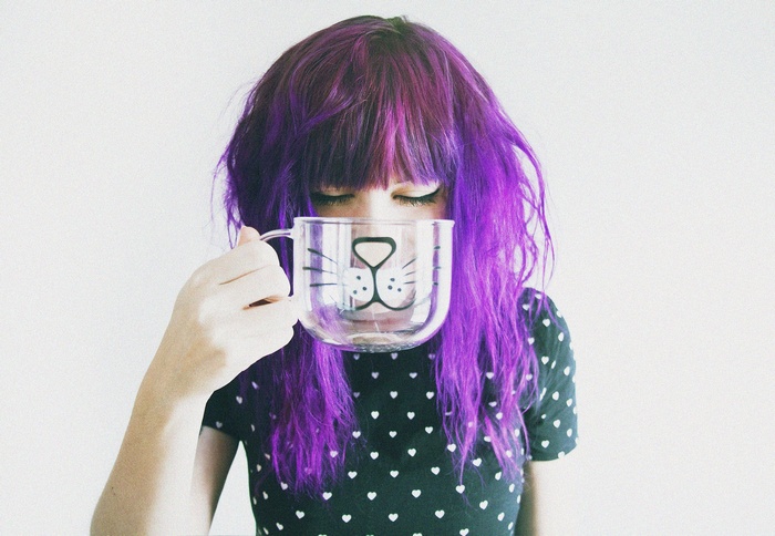 Woman with purple hair holding a cat mug
