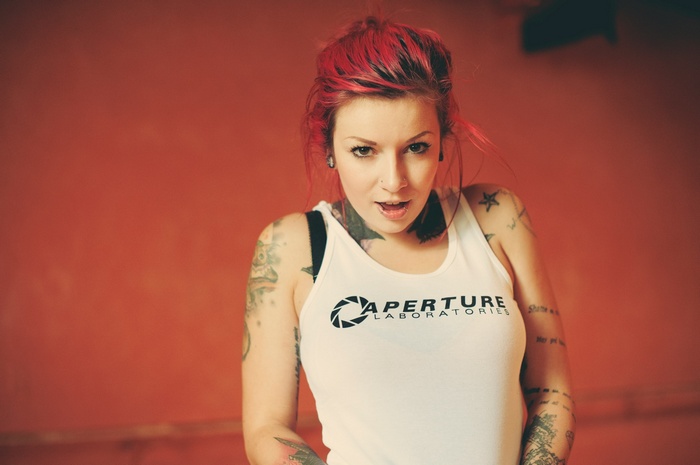 Woman with red hair and tattoos wearing Aperture Laboratories tank top