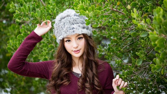 Asian woman wearing a furry hat and maroon sweater