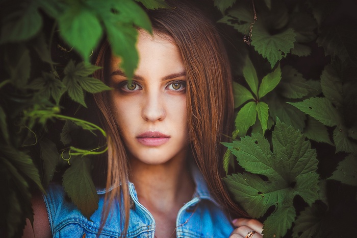 Portrait of a young woman surrounded by green leaves
