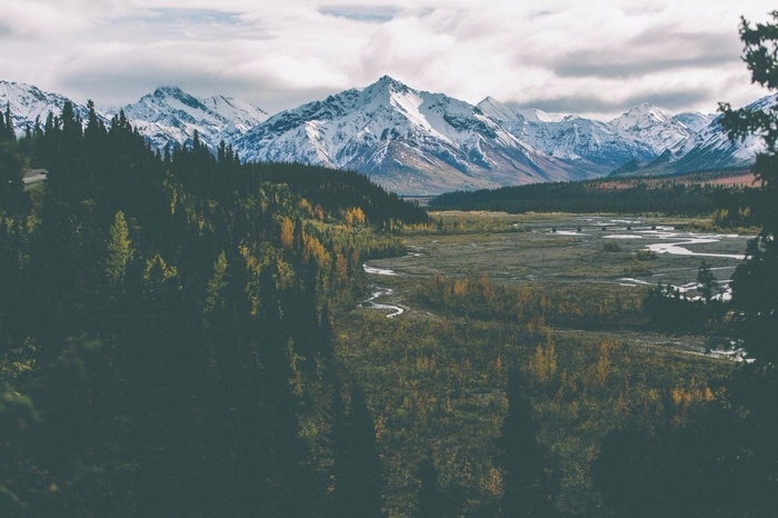 Snow-capped mountains and a winding river in a forest valley